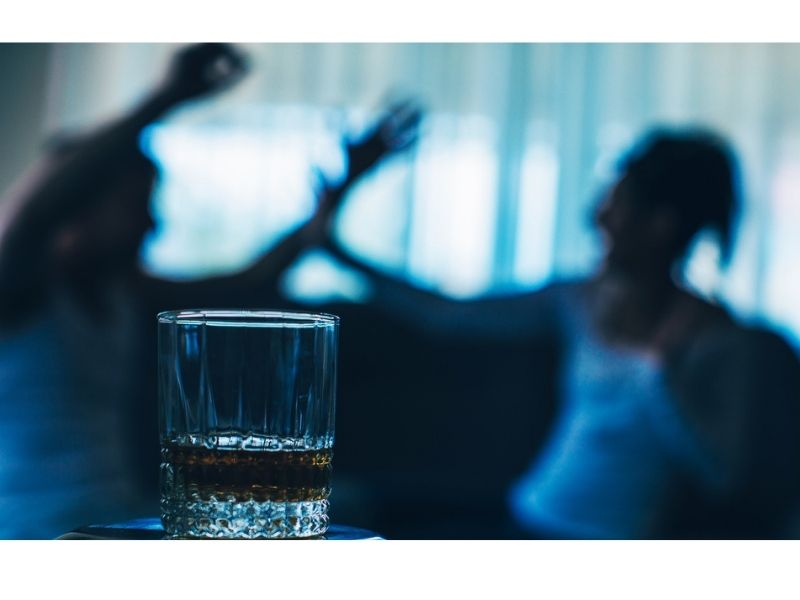 couple fighting with glass with alcoholic drink on foreground